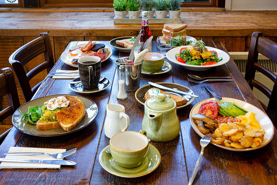 Overview of a laid table for four with delicious looking breakfasts served in a garden centre cafe.
