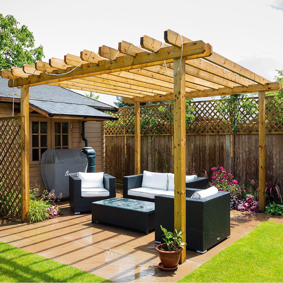 Close up of a family entertainment area in a garden design. It features some rattan furniture and a wooden pergola.. There is a covered area with a gas barbeque.